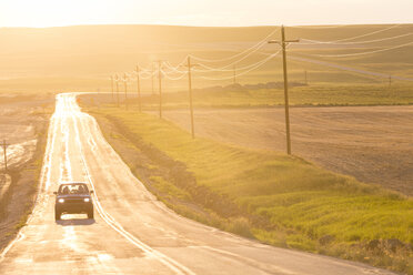 Car traveling on long straight open highway at sunset. - MINF08835