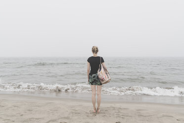 Rückenansicht einer Frau, die am Strand steht und in die Ferne schaut - CHPF00499