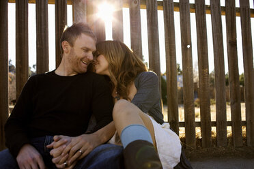 Couple sits against a fence. - AURF00593