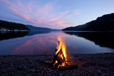 Lagerfeuer mit Sonnenuntergang, der sich auf dem See in Idaho spiegelt. - AURF00597