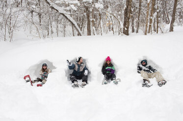 Four young men and women sit in the snow with snowshoes on in Milcreek Canyon, Salt Lake City, Utah. - AURF00623