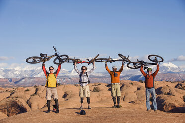 Four young men hold their bikes above their heads on the Slickrock Trail, Moab, UT. - AURF00637