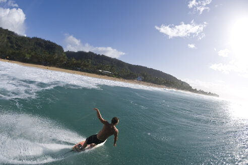 Ein junger Mann surft in Pupukea, an der Nordküste von Oahu, Hawaii, an der Kamera vorbei. - AURF00679