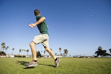 Ein junger Mann lässt an einem sonnigen kalifornischen Nachmittag in Ventura, Kalifornien, einen Drachen steigen. - AURF00697