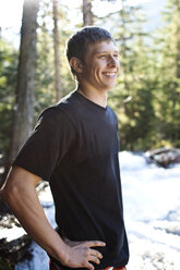 Ein junger Mann lächelt, während er neben einem reißenden Fluss in Idaho steht. - AURF00722