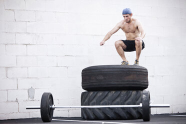 A young man jumps on tires while doing a fitness boot camp. - AURF00756