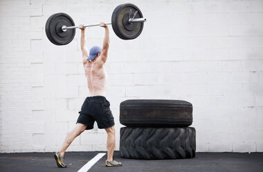 A young man lifts weights during a fitness boot camp. - AURF00757