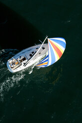 Aerial view of a sailing yacht with a colorful spinnaker cruising in Pittwater on the North Shore from Sydney, Australia. - AURF00776