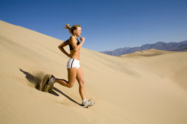 Eine junge Frau läuft eine steile Sanddüne im Death Valley, Kalifornien, hinunter. - AURF00778