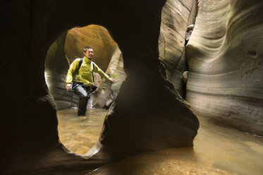 Ein asiatischer Mann beim Canyoning durch einen wasserreichen Canyon im Zion National Park, Springdale, Utah. - AURF00790