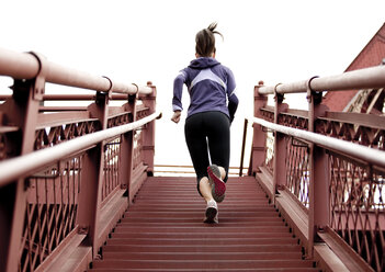 An athletic female in a purple jacket running stairs in Portland, Oregon. - AURF00795