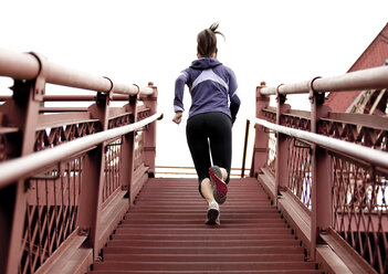 Eine sportliche Frau in einer lila Jacke beim Treppenlaufen in Portland, Oregon. - AURF00795