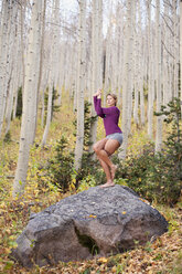 Eine junge Frau nimmt eine Yogastellung auf einem Felsen im Big Cottonwood Canyon in der Nähe von Salt Lake City, UT, ein. - AURF00818
