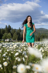 A young women laughs while dancing in a field of wild flowers. - AURF00822