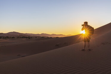 Africa, Namibia, Namib desert, Naukluft National Park, photographer on dune during sunrise - FOF10080