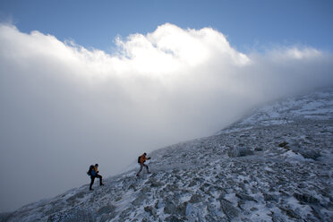 Zwei Männer wandern auf der Boott Spur Link, als sich der Sturm legt und den Blick auf die Tuckerman's Ravine und den Gipfel des Mt. Washington freigibt. - AURF00919