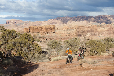 Zwei junge Männer fahren mit ihren Fahrrädern über den Slickrock auf dem Amasa Back Trail in Moab, UT. - AURF00960