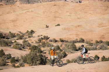 Zwei Mountainbiker machen eine Pause während einer Fahrt auf dem Slickrock Trail, Moab, UT. - AURF00961