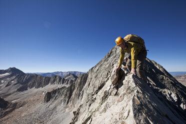 Two young men crossing an exposed ridge line with the summit behind them. - AURF00968