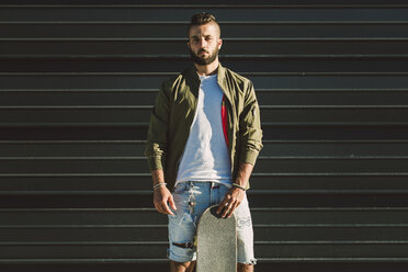 Portrait of young man with skateboard - RAEF02108