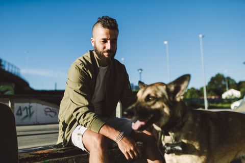 Porträt eines zufriedenen jungen Mannes mit seinem Hund, lizenzfreies Stockfoto