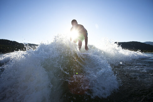 Ein sportlicher Mann surft hinter einem Wakeboard-Boot bei Sonnenuntergang in Idaho. - AURF00995