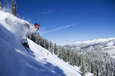 Ein sportlicher Snowboarder springt an einem sonnigen Tag im Pulverschnee in Colorado von einer Klippe. - AURF00998