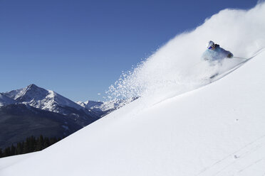 Ein sportlicher Skifahrer zieht an einem sonnigen Tag in Colorado seine Schwünge im frischen Pulverschnee. - AURF01000