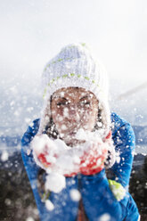 A beautiful young woman blowing snow on a winter hike in Idaho. - AURF01030