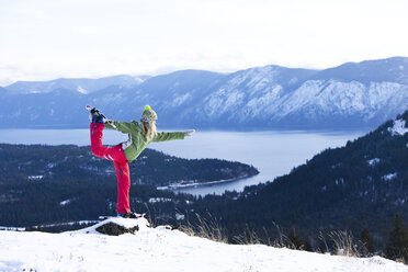 Eine schöne junge Frau macht Yoga beim Schneeschuhwandern über einem See in Idaho. - AURF01033