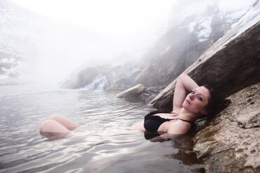 Eine schöne Frau, die sich an einem heißen Wasserfall in Montana entspannt. - AURF01034