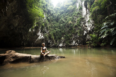 A beautiful young woman adventuring deep into a remote jungle pool relaxes in Thailand. - AURF01047