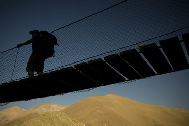 Ein Rucksacktourist überquert eine Brücke auf dem Weg in die chilenischen Anden. - AURF01049