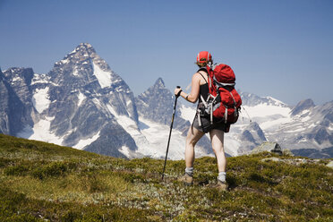 Eine Wanderin wandert auf einem Pfad in den Selkirk Mountains mit Blick auf den Mount Sir Donald. - AURF01060