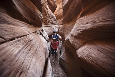A couple hiking through a slot canyon in Utah. - AURF01071