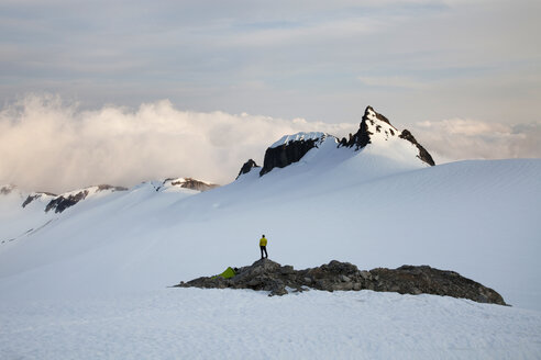 Ein Kletterer steht beim Klettern in den North Cascades, WA, auf einem Felsvorsprung inmitten eines Gletschers. - AURF01080