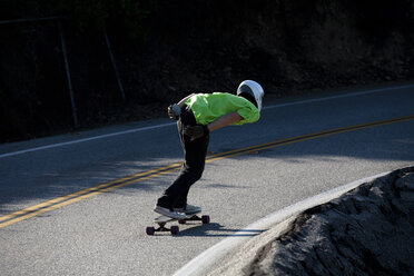 Ein Downhill-Skateboarder fährt einen steilen Berg hinunter. - AURF01086