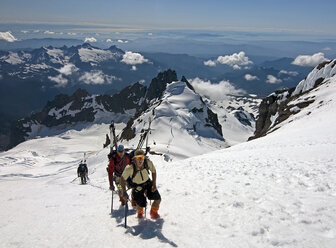 A father and son climb the upper slopes of Mt. Baker later skiing from the summit on a beautiful August day in the Mt. Baker Wilderness, Washington State. - AURF01092