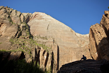 Ein Wanderer ruht sich auf einem Felsen im Zion National Park aus. - AURF01096