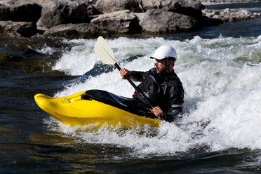 A male kayaker in a playboat rides the rapids of Brennan's Wave, Missoula, Montana. - AURF01116