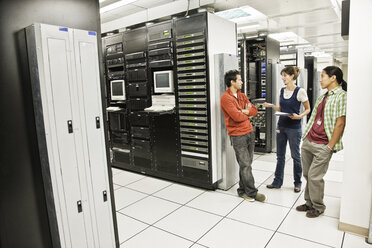 Drei multiethnische Techniker arbeiten in einem großen Computerserverraum. - MINF08928
