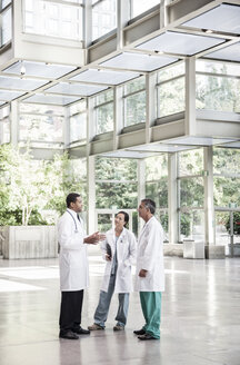 Gemischte Gruppe von Ärzten trifft sich in der Lobby eines großen Krankenhauses - MINF08949