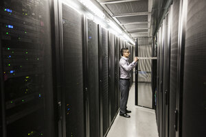 Hispanic man technician doing diagnostic tests on computer servers in a large server farm. - MINF08959