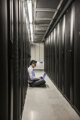 Hispanic man technician doing diagnostic tests on computer servers in a large server farm. - MINF08960
