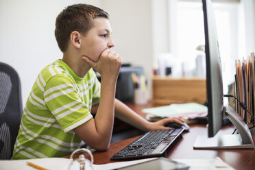 Young Caucasian boy at work on a desk top computer system. - MINF08976