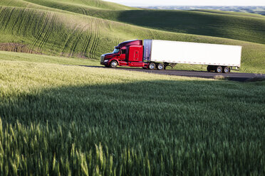 Ein Lastwagen fährt bei Sonnenuntergang durch die Weizenfelder im östlichen Washington, USA. - MINF09058
