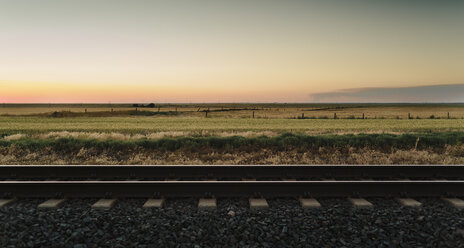 Eisenbahnschienen, die in der Abenddämmerung durch eine ländliche Landschaft führen. - MINF09063