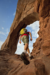 A man hiking below an arch in Arches National Park, Utah. - AURF01128