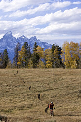 A man bikes with the Tetons in the background in Wyoming. - AURF01142