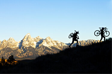 A man and a woman hike their bikes up a hill in Wyoming. - AURF01143